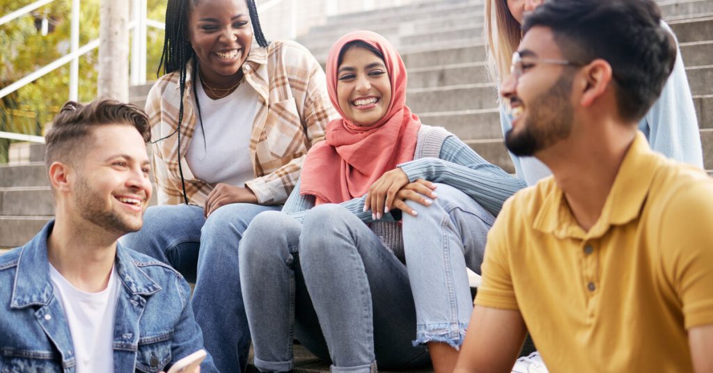 A diverse group of students sitting on some concrete steps. Everyone is smiling and relaxed, talking with one another.